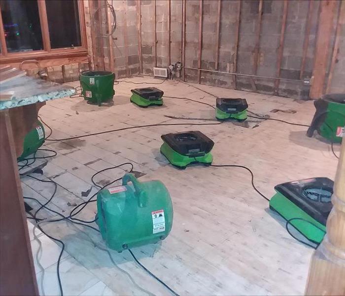 This is the same room that the drywall and the floor has been removed. Air movers are drying the materials. 