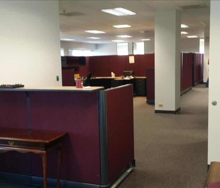 This is a photo of an office, with a desk in the foreground and cubicles in the background. 